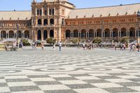 a crowd is walking around in the courtyard of an ornate building with circular patterns on stone flooring