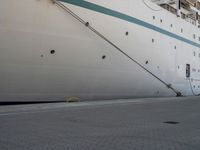 a large white cruise ship is parked in the dock area, with ropes hanging from it's side