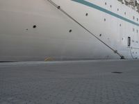 a large white cruise ship is parked in the dock area, with ropes hanging from it's side