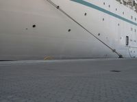 a large white cruise ship is parked in the dock area, with ropes hanging from it's side