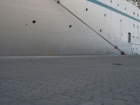 a large white cruise ship is parked in the dock area, with ropes hanging from it's side