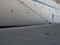 a large white cruise ship is parked in the dock area, with ropes hanging from it's side