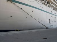 a large white cruise ship is parked in the dock area, with ropes hanging from it's side