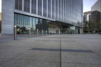 a building on a street with a large glass front and a building across the street with poles outside