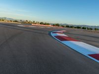 a photo of a dirt race track with sun setting in the distance of the track