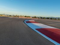 a photo of a dirt race track with sun setting in the distance of the track