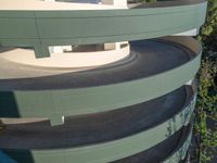 a red, blue and green skate board on the edge of a curved driveway and building