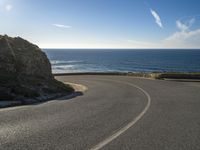 there is a curved curve near the ocean, road or highway with sea view and blue sky