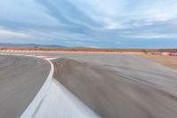 a photo of a dirt race track with sun setting in the distance of the track