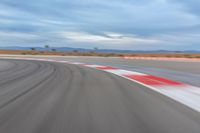 a photo of a dirt race track with sun setting in the distance of the track