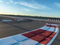 a photo of a dirt race track with sun setting in the distance of the track