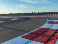 a photo of a dirt race track with sun setting in the distance of the track