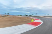 a photo of a dirt race track with sun setting in the distance of the track