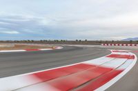 a photo of a dirt race track with sun setting in the distance of the track