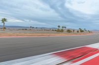 a photo of a dirt race track with sun setting in the distance of the track