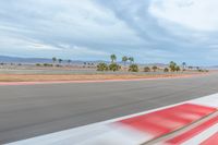 a photo of a dirt race track with sun setting in the distance of the track