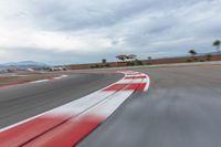 a photo of a dirt race track with sun setting in the distance of the track