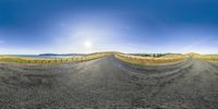 the sun shines brightly over a curved asphalt road, in a low perspective 360 - angle