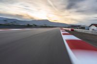 a photo of a dirt race track with sun setting in the distance of the track