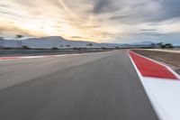 a photo of a dirt race track with sun setting in the distance of the track