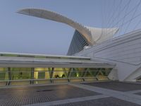 a curved building with a large arched roof in the evening sun lit area near the entrance