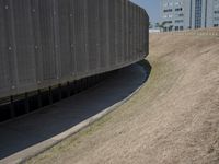 the back wall of a building that has been added to be curved and empty with grass growing out to the ground
