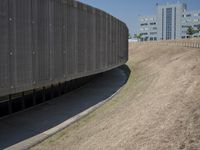 the back wall of a building that has been added to be curved and empty with grass growing out to the ground