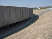 the back wall of a building that has been added to be curved and empty with grass growing out to the ground