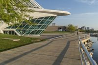 a curved building with a glass front next to another building in a city park area