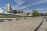 a curved building with a glass front next to another building in a city park area