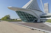a curved building with a glass front next to another building in a city park area