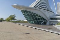 a curved building with a glass front next to another building in a city park area