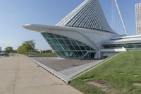 a curved building with a glass front next to another building in a city park area