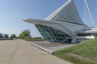 a curved building with a glass front next to another building in a city park area