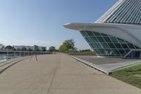 a curved building with a glass front next to another building in a city park area