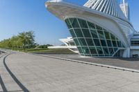 a curved building with a glass front next to another building in a city park area