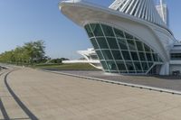 a curved building with a glass front next to another building in a city park area