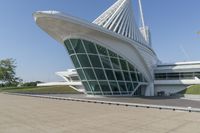 a curved building with a glass front next to another building in a city park area