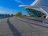 a curved building with a glass front next to another building in a city park area