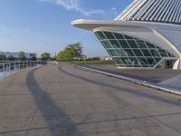 a curved building with a glass front next to another building in a city park area