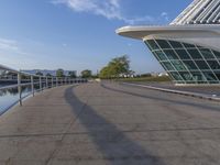 a curved building with a glass front next to another building in a city park area