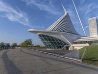 a curved building with a glass front next to another building in a city park area