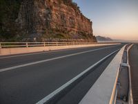 a curved highway that goes over the rocks to the ocean's edge next to it