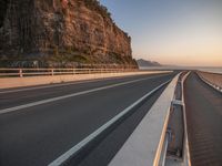 a curved highway that goes over the rocks to the ocean's edge next to it