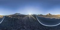 this is a 360 - camera lens of a curved highway near the mountains and in a straight line there is an empty road