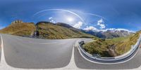 360 - pan photo of curved mountain road taken from camera angle with sun shining through clouds