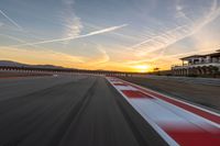 a photo of a dirt race track with sun setting in the distance of the track