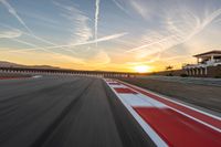 a photo of a dirt race track with sun setting in the distance of the track