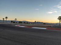 a photo of a dirt race track with sun setting in the distance of the track