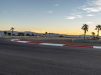 a photo of a dirt race track with sun setting in the distance of the track